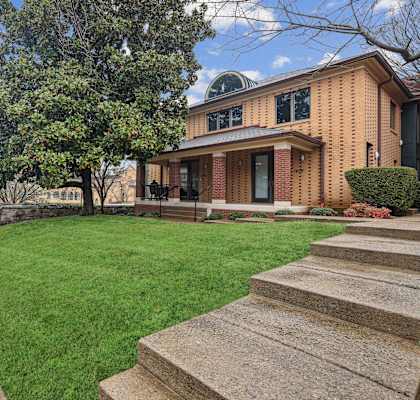 A house with a green lawn and a tree in front.