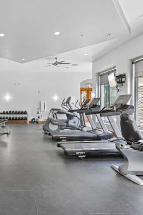 A spacious gym with a variety of equipment including treadmills, weights, and a bench press.