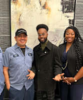 Four people wearing blue shirts with the name "EJ" on them stand in front of a wall.
