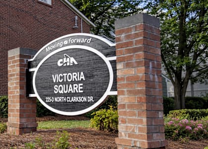 A sign for Victoria Square is in front of a brick building.