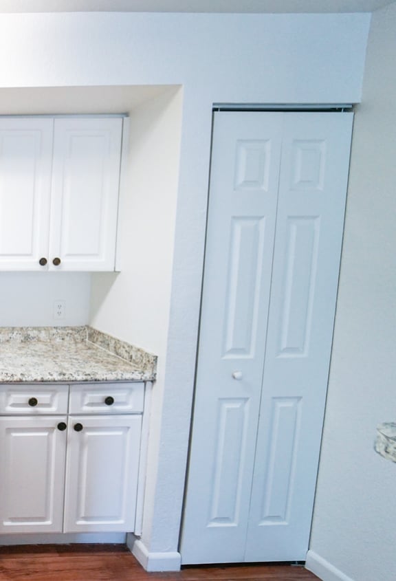 Kitchen with hardwood style flooring, white cabinetry and white appliances
