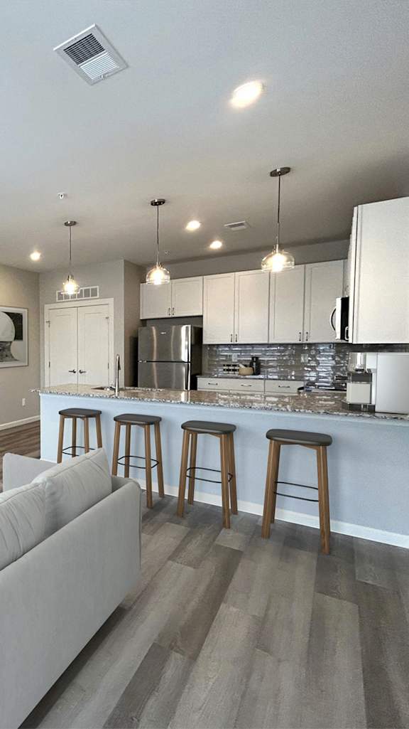A modern kitchen with a bar area and wooden flooring.