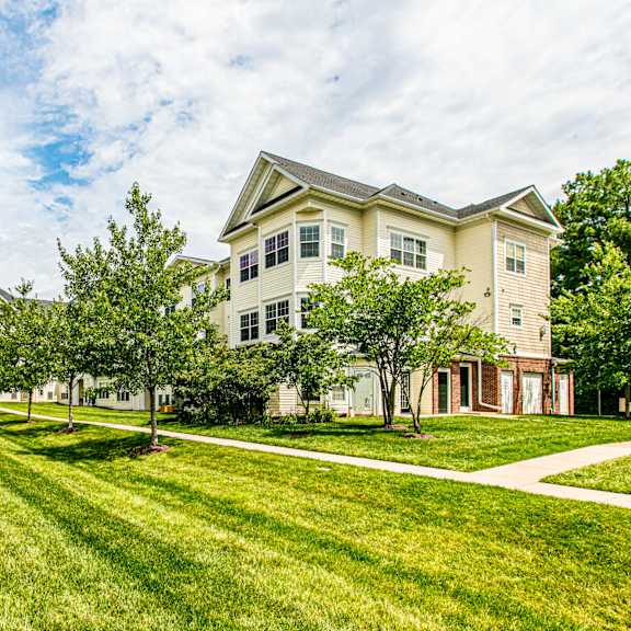 A brick building with a balcony and a tree in front. at Barrington Park Apartments, Manassas