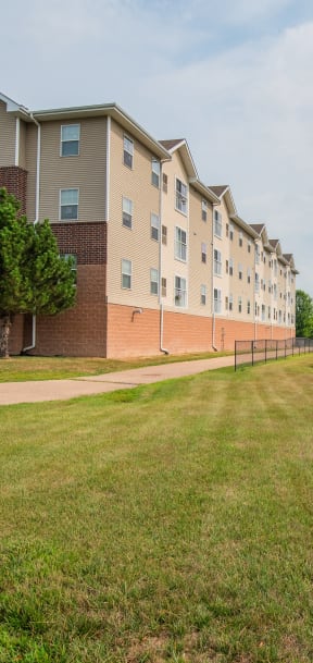 a nature adjacent building with grass and a bike path
