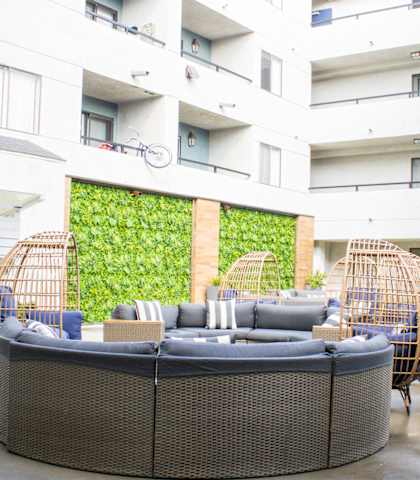 A large wicker sofa sits in the middle of a courtyard.