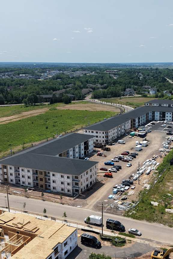 A person is standing in a parking lot in front of apartment buildings.
