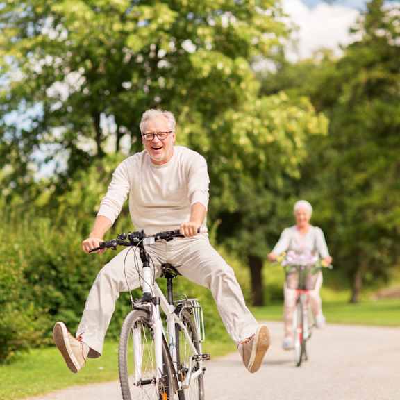 two women riding bicycles down the street on bikes