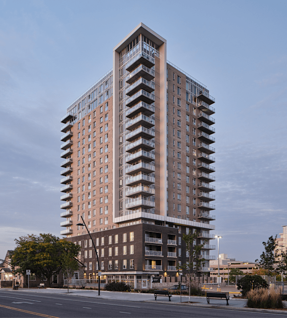 A tall building with a brown facade stands in the middle of a street.
