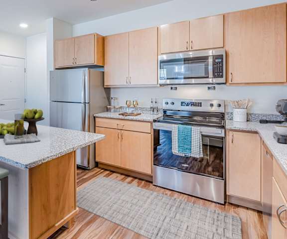 A kitchen with wooden cabinets and a white island.