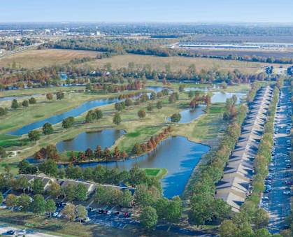an aerial view of a neighborhood with a pond in the middle of it