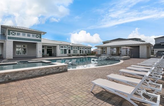 a swimming pool with lounge chairs in front of a building