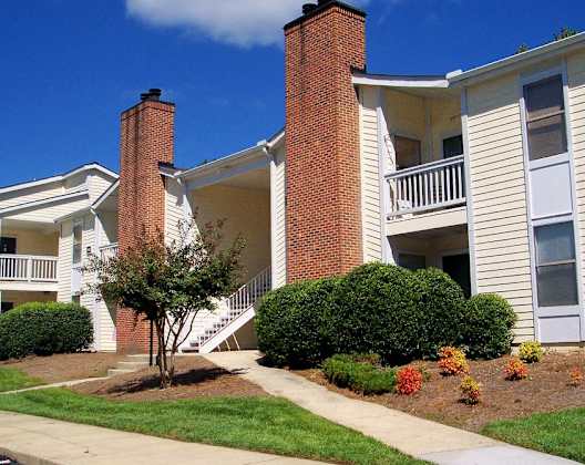 A white house with a red brick chimney. at Fox Hollow Apartment Homes, High Point, NC, 27265