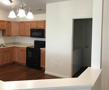 an empty kitchen with wooden cabinets and black appliances at Shaker Square in Lebanon, IN 46052