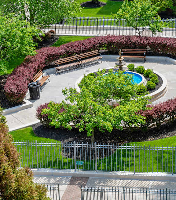 A park with a fountain surrounded by benches and trees.