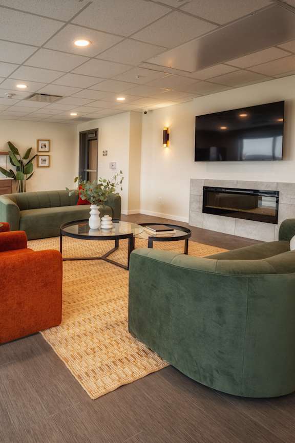 A living room with a grey floor and a green couch. at Unite Apartments, Fargo, ND, 58103