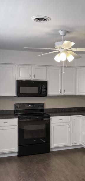 a kitchen with white cabinets and a black stove and refrigerator