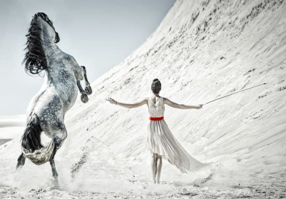 a woman in a white dress is standing next to a horse