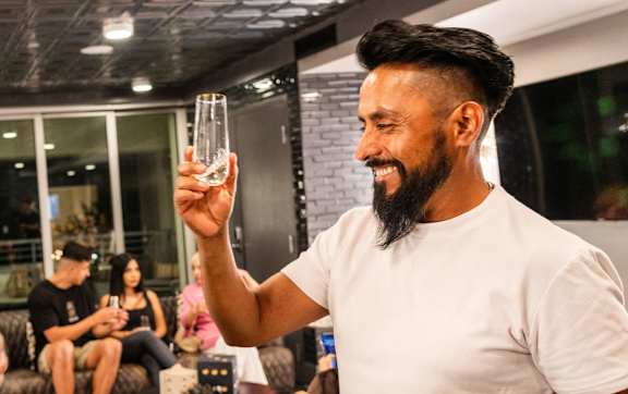 Two men are toasting with drinks in a modern indoor setting.