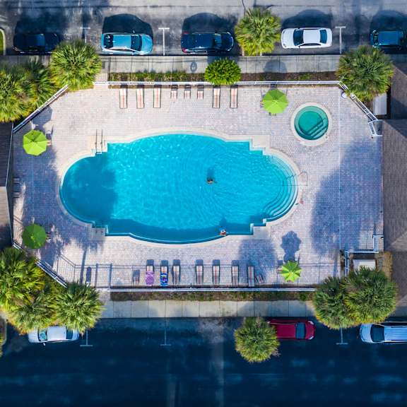 An aerial view of a swimming pool surrounded by lounge chairs and palm trees.