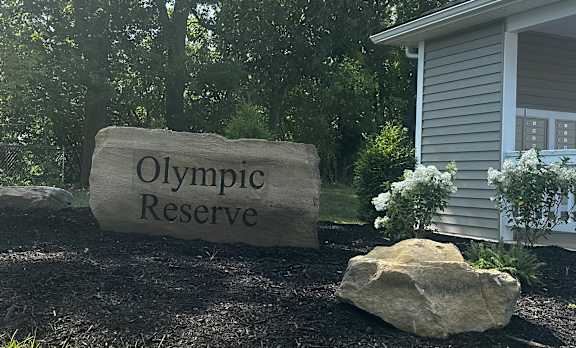 a stone sign that reads olympic reserve in front of a house