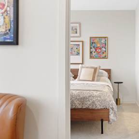 A bedroom with a bed, a chair, and pictures on the wall.