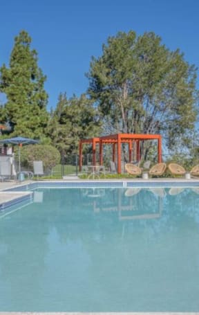 a swimming pool with chairs and trees in the background at The Resort at Encinitas Luxury Apartment Homes, Encinitas, California
