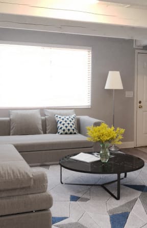 a living room with a couch and a table with a vase of yellow flowers