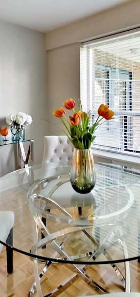 a dining room with a glass table and chairs and a large window