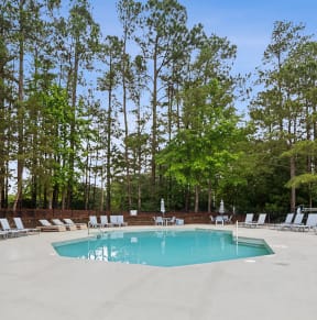 our resort style pool is surrounded by chairs and trees