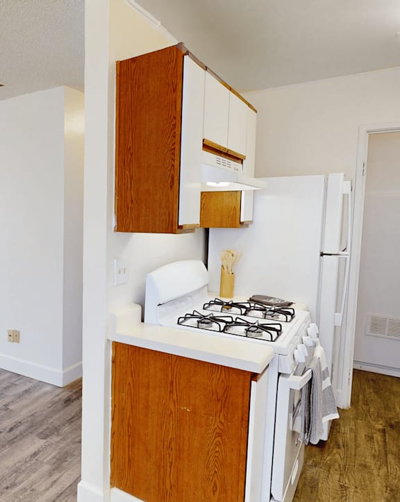 A kitchen with a white stove and wooden cabinets.