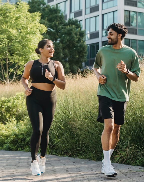 a woman and a man running down a sidewalk in front of a building