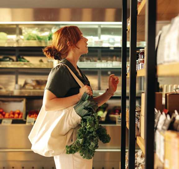 a woman walking through a clothing store with a bag