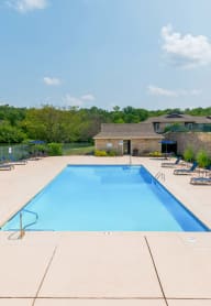a swimming pool with blue chairs around it next to a river