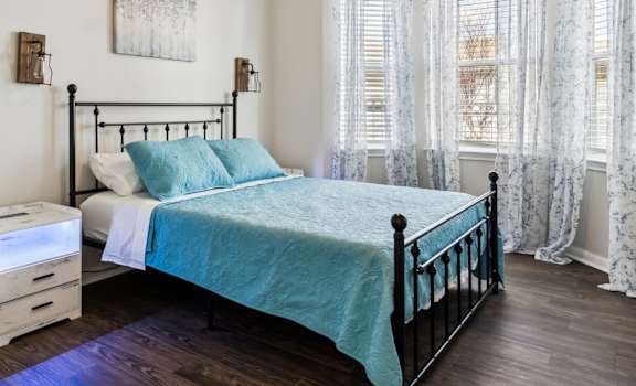 A bedroom with a bed, nightstand, and window.