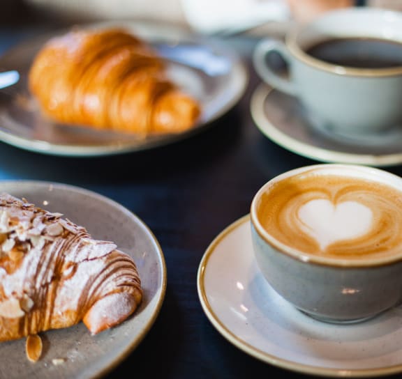 a cup of coffee and a croissant on a table at West Park Village, Los Angeles, California