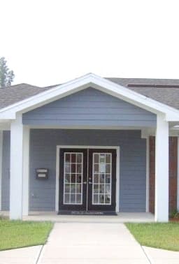 the front of a brick building with a sign and a tree