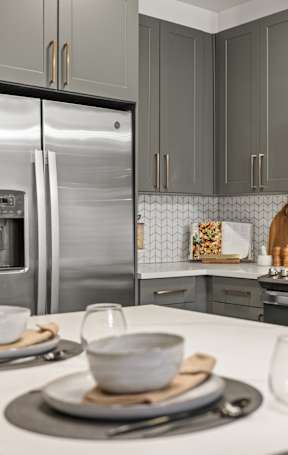 A modern kitchen with a white countertop and stainless steel appliances.