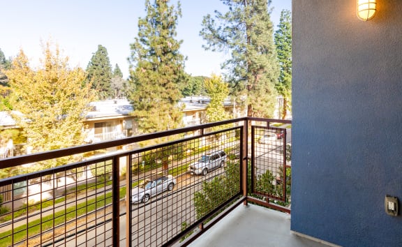 the balcony has a view of the street and trees