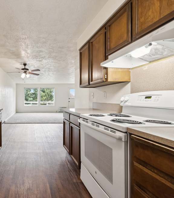 A kitchen with brown cabinets and a white stove top oven.