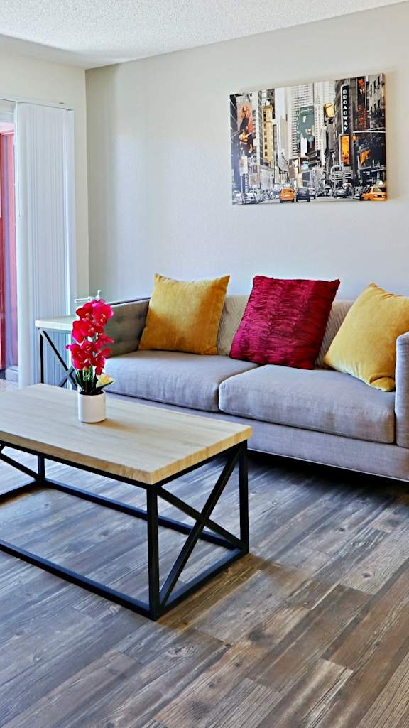 A living room with a grey couch and a wooden coffee table. at Spring Meadow Apartments, Glendale, AZ, 85302