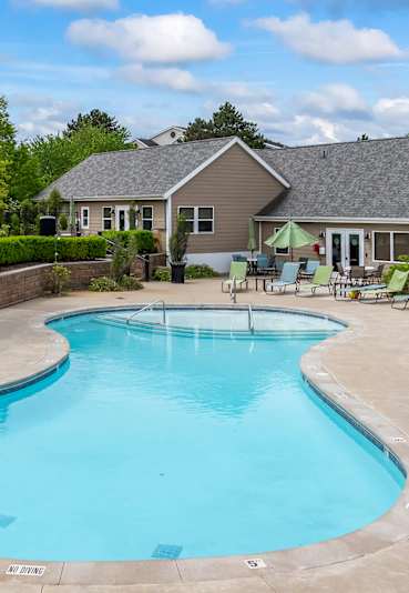  A swimming pool surrounded by lounge chairs and a building in the background.