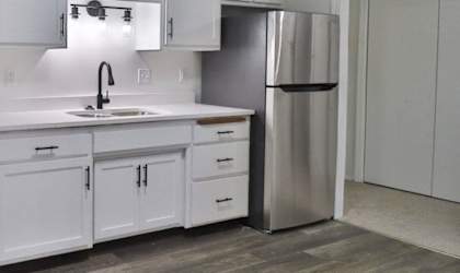 A modern kitchen with white cabinets and a black stove top oven.
