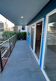 A wooden deck with a green railing overlooks a lush green yard.