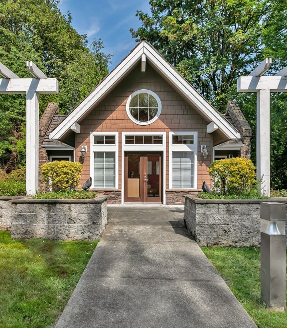 the front of a house with a walkway and two white pergolas