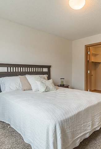 A bedroom with a bed, nightstand, and carpeted floor.