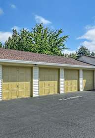 A two-story garage with yellow doors and a brown roof.