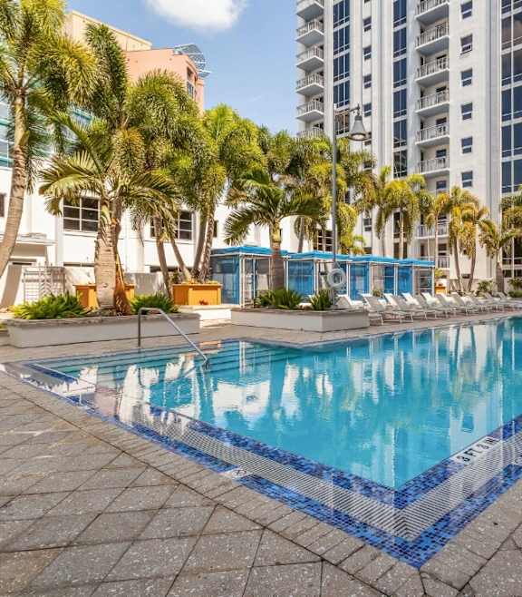 a large swimming pool with palm trees and a building in the background at Paramount on Lake Eola, Florida, 32801