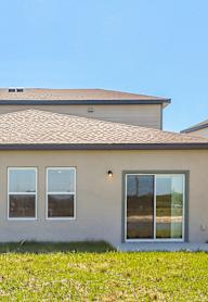 A house with a grey roof and beige walls with a window on the right side.
