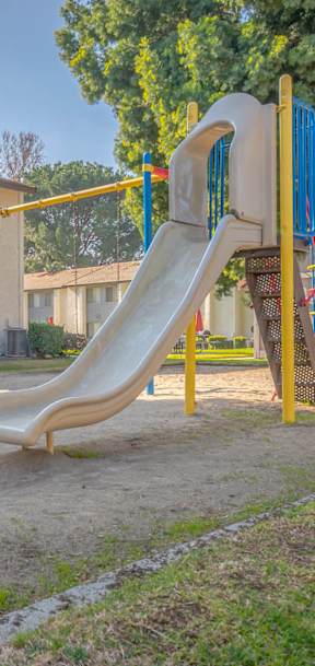 A playground with a yellow slide and a red ladder.
