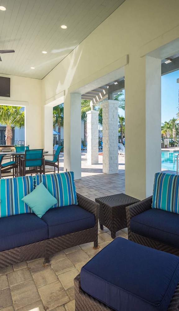 a patio with couches and chairs and a pool in the background at Alaqua Apartments, Florida, 32258